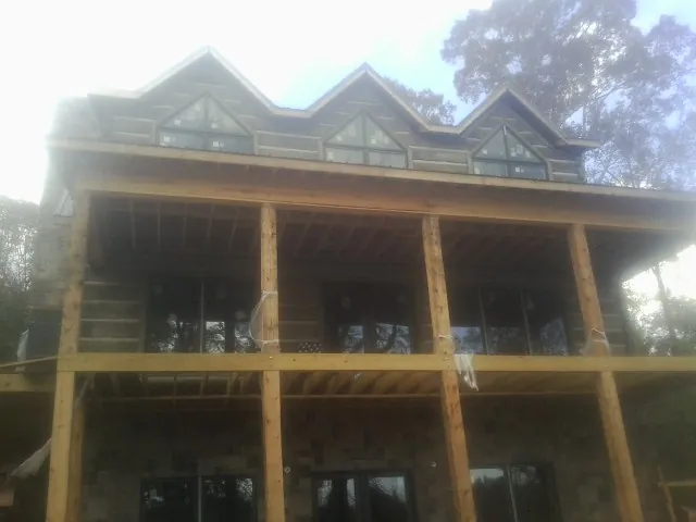 Dormers and porch framing on a large log home under construction — Roof Coating work by our crew in Ashton