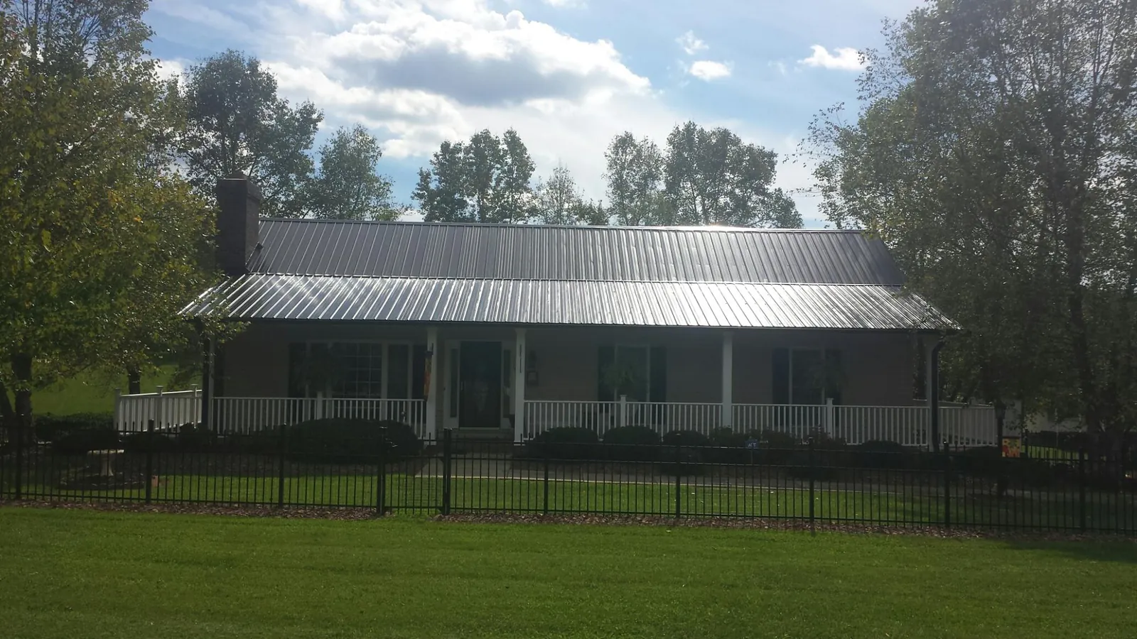 Gray metal roof on a brick ranch with a full width front porch — Gutter Guard Installation work by our crew in Ashton